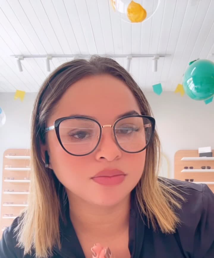 Cliente usando armação gatinho de acetato preto com haste dourada, dentro da loja.