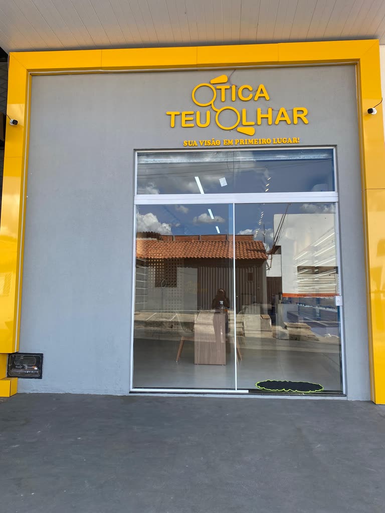 Fachada da loja de Água Branca do Piauí, com moldura amarela e o logo completo em relevo sobre a parede cinza.